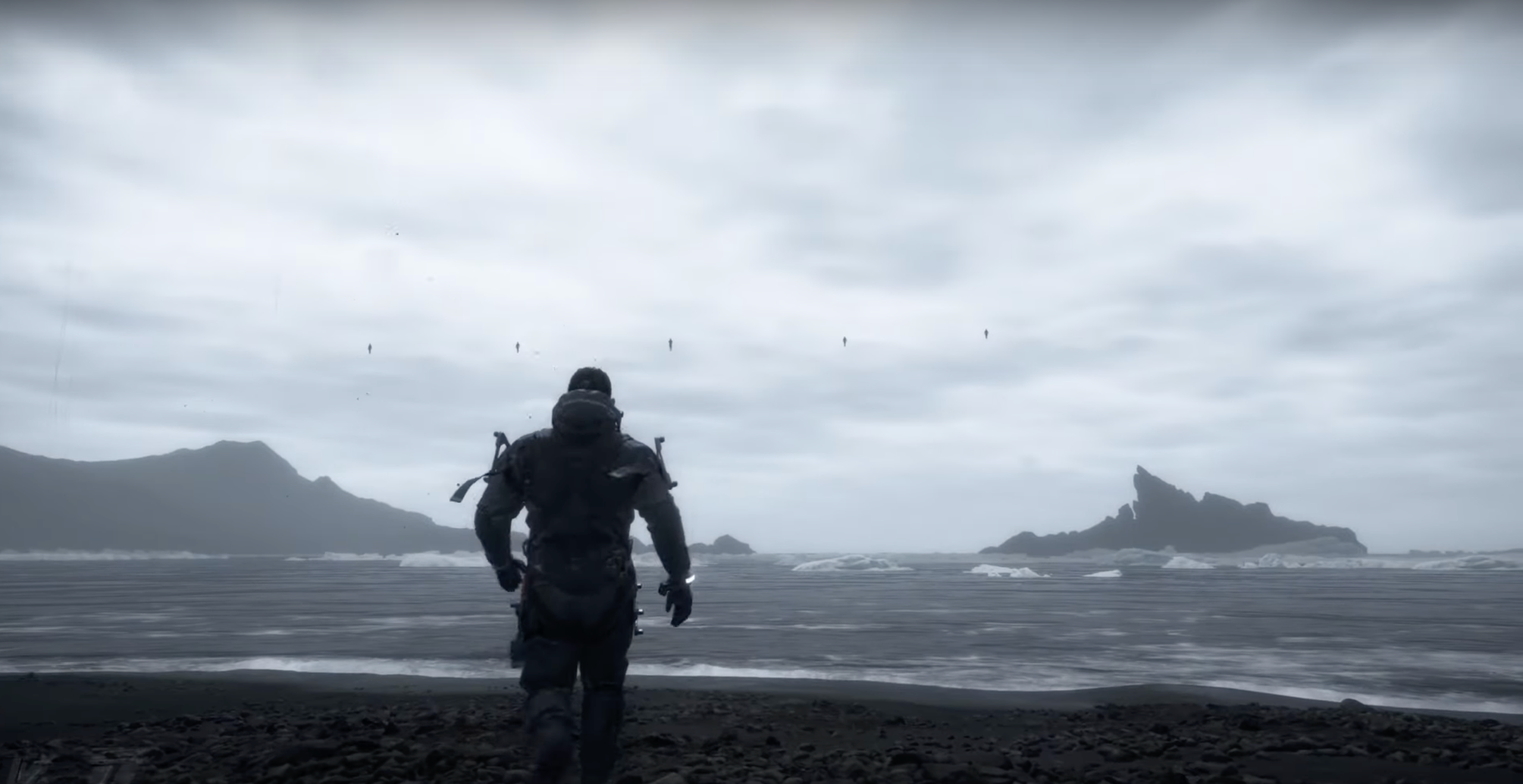 Screenshot aus Death Stranding, der den Strand und eine Rückenaufnahme von Sam Porter Bridges zeigt.