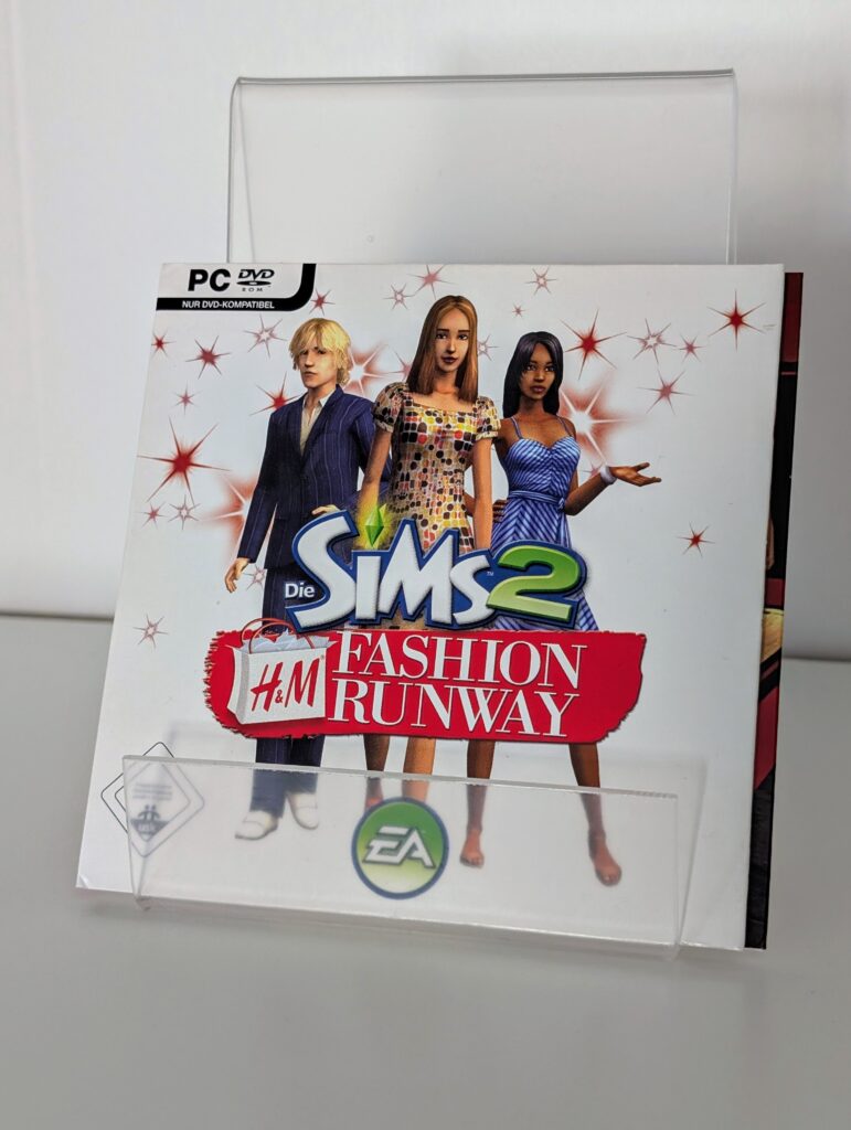 Das Bild zeigt die Verpackung der Die Sims 2 H&M Fashion Runway erweiterung. Darauf sind drei posierende Spielfiguren vor weißem Hintergrund zu sehen.
